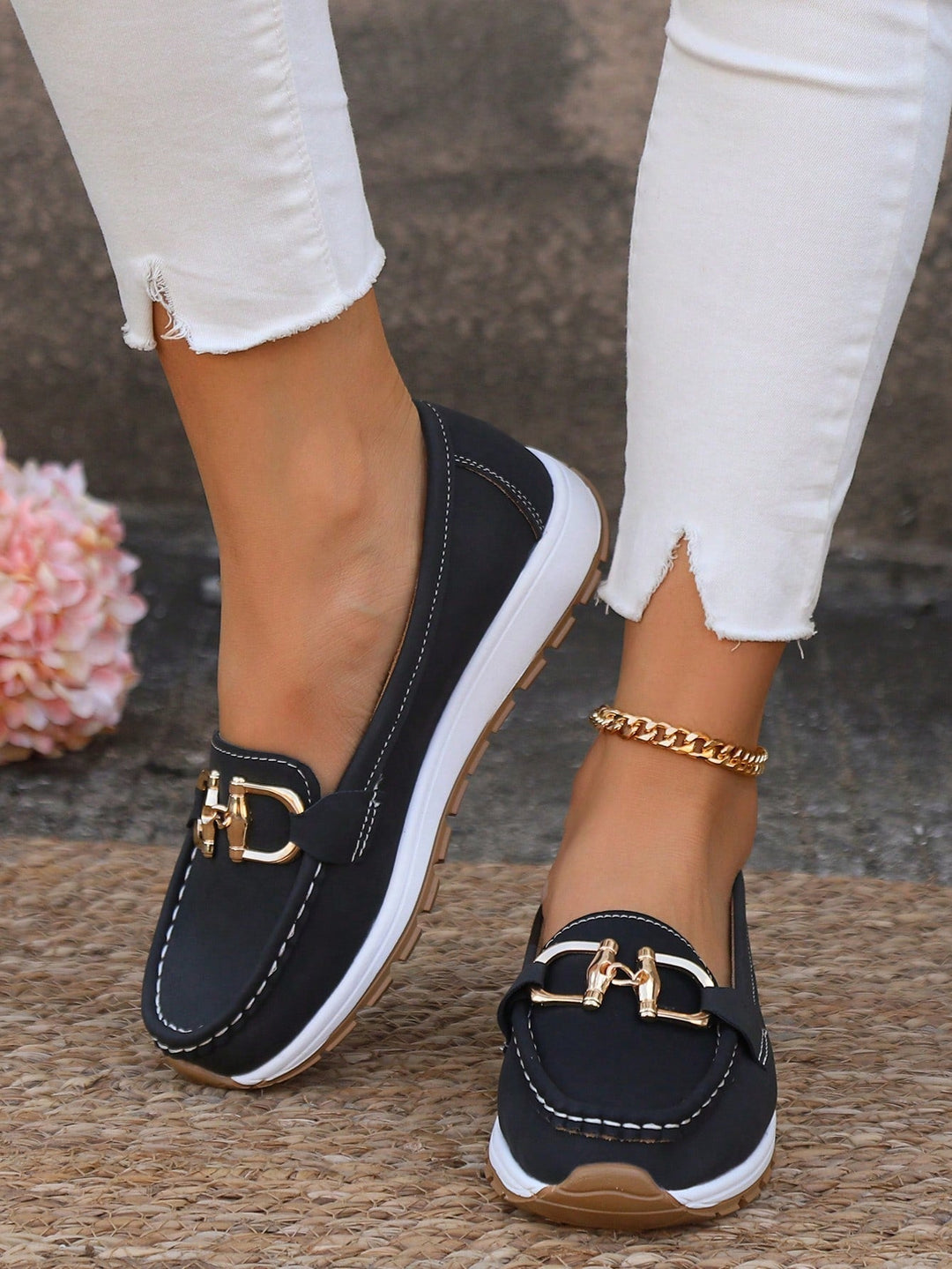 Black chain detail slip-on loafers with gold hardware, white sole, stitched edges.