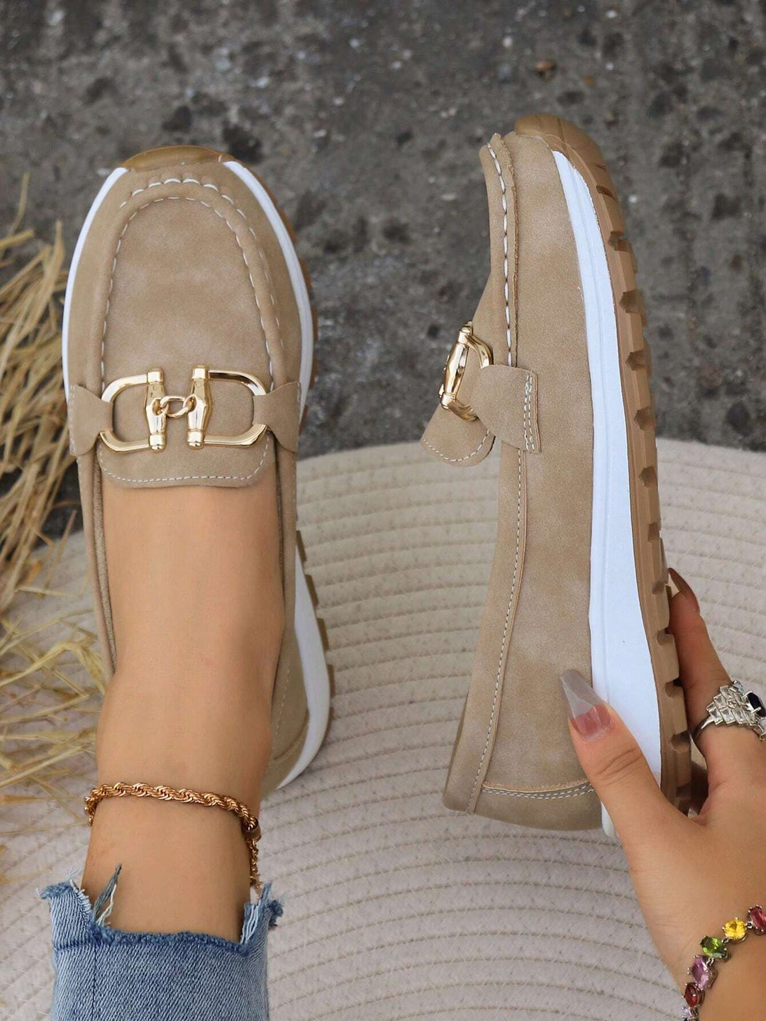 Pair of khaki slip-on loafers showing front moc toe and gold chain bar detail.