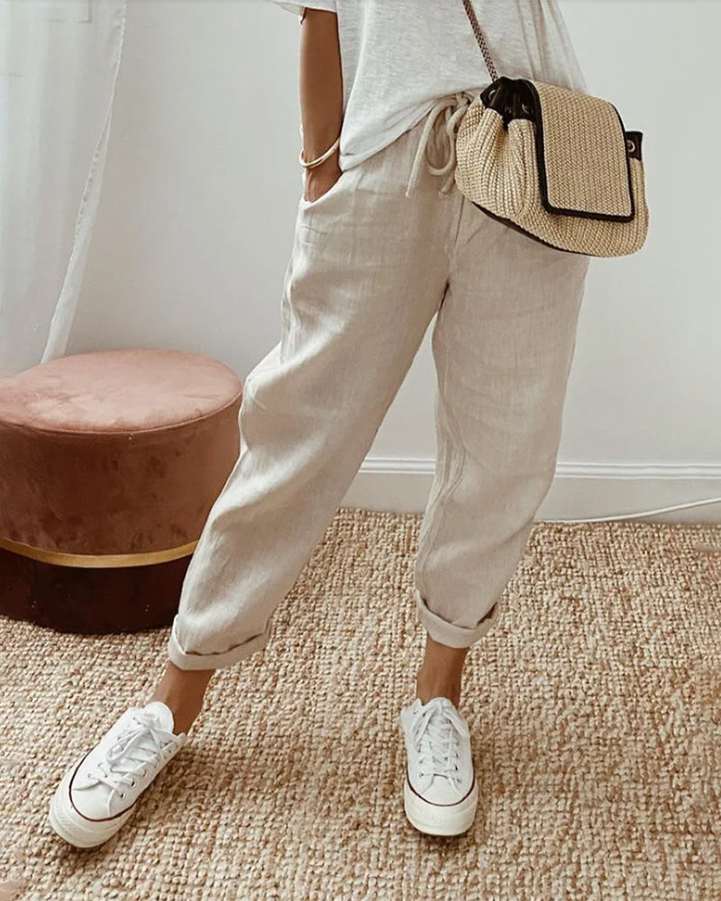 Beige relaxed drawstring pants with cuffed hem and adjustable waist tie.