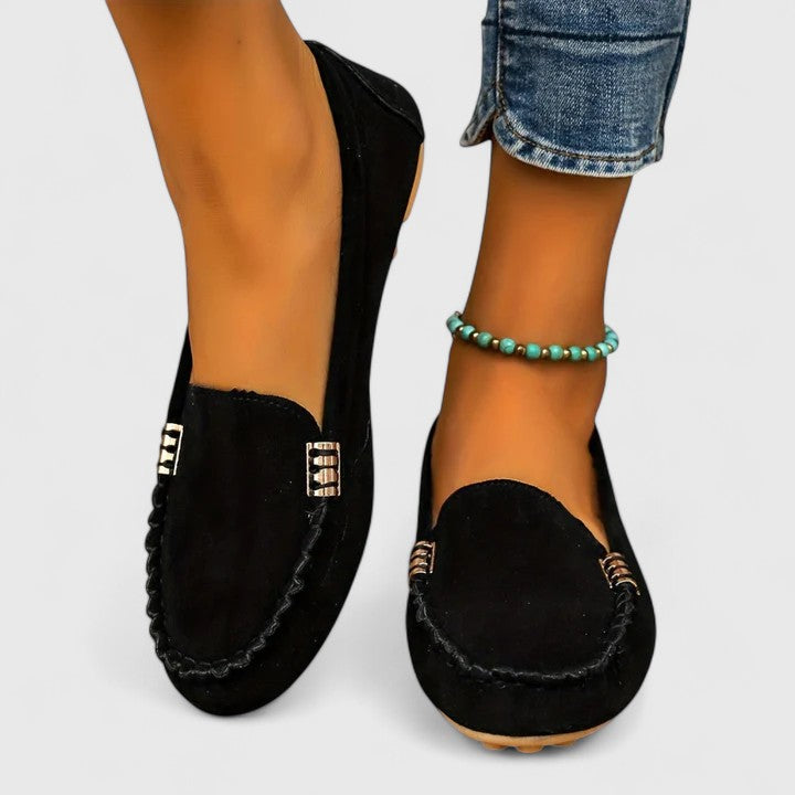 Black suede slip-on loafers with metal buckle accent and stitched moc toe