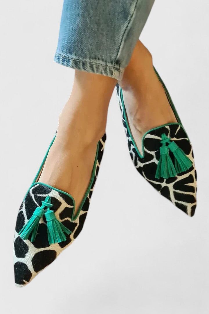 Tassel slip-on flats with green trim and cow-print upper, featuring green tassels