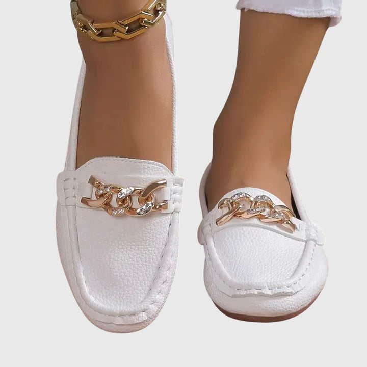Pair of white slip-on loafers with gold chain ornament on the vamp and stitched edges.