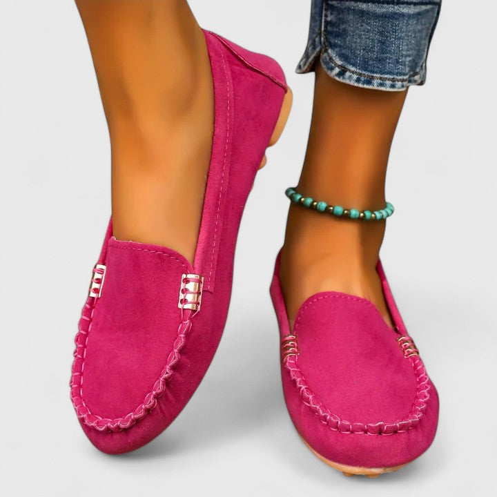 Pink suede slip-on loafers with metal buckle detail and stitched moccasin toe