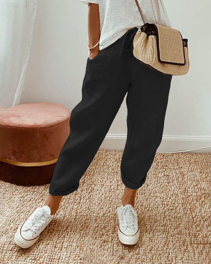 Black relaxed drawstring pants with cuffed hem and adjustable waist tie.