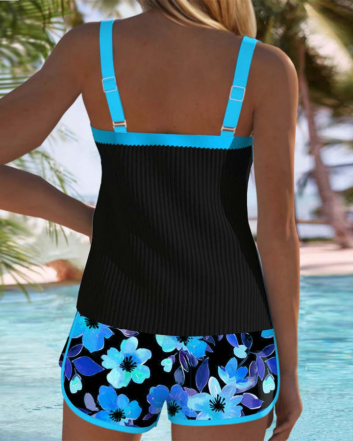 Black tummy control tankini with turquoise back straps and floral shorts, rear