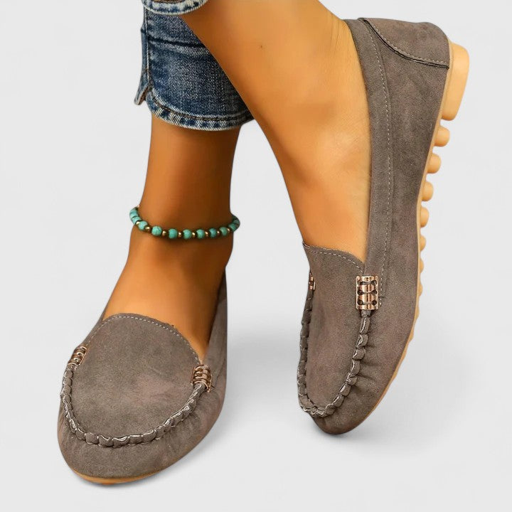 Gray suede slip-on loafers with metal buckle detail and round toe profile