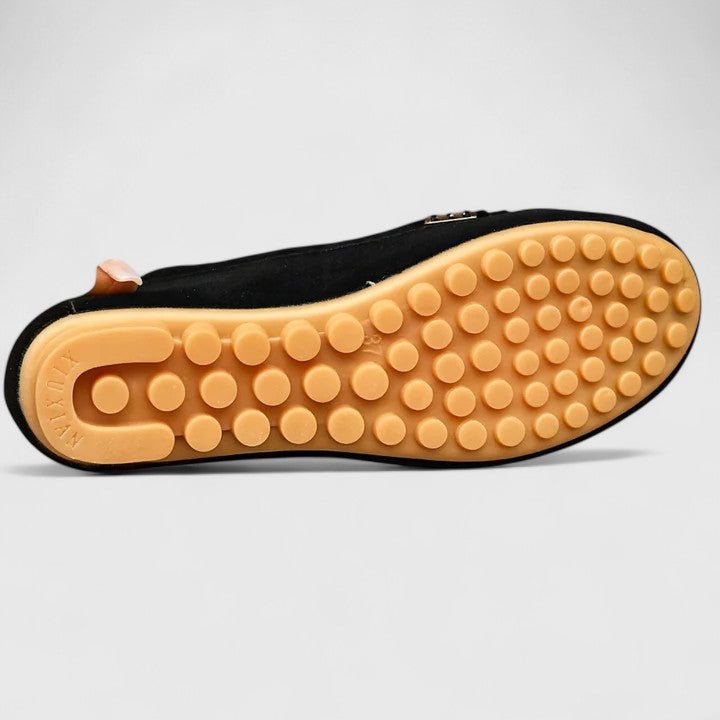 Black suede slip-on loafer showing textured rubber outsole with tread dots