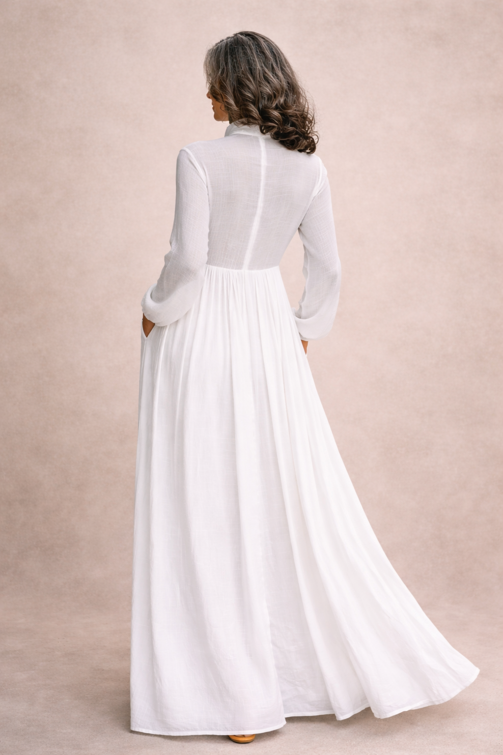 Back view of white button-front maxi dress with long sleeves and flowing skirt