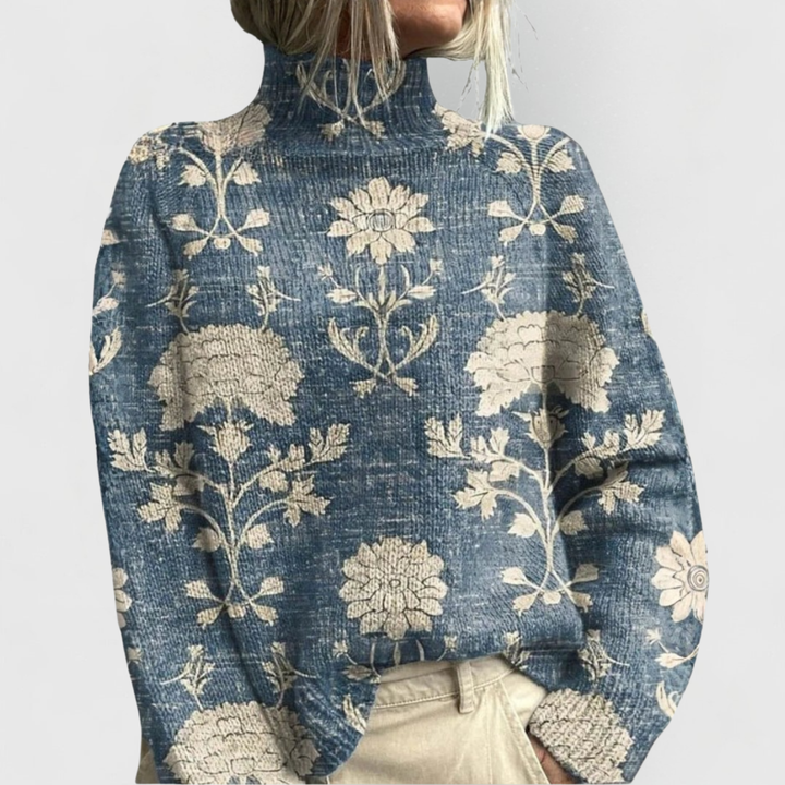 Blue turtleneck sweater with beige floral and vine pattern across the front.