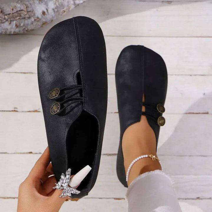 Black slip-on flats with lace-up front and round button detail at vamp