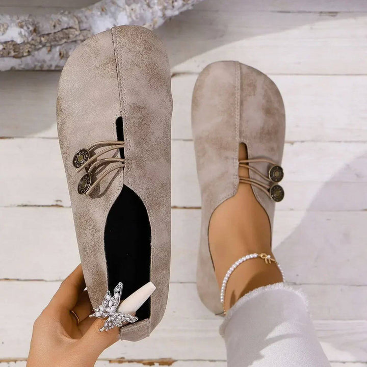 Light brown slip-on flats with lace-up front and two round button accents