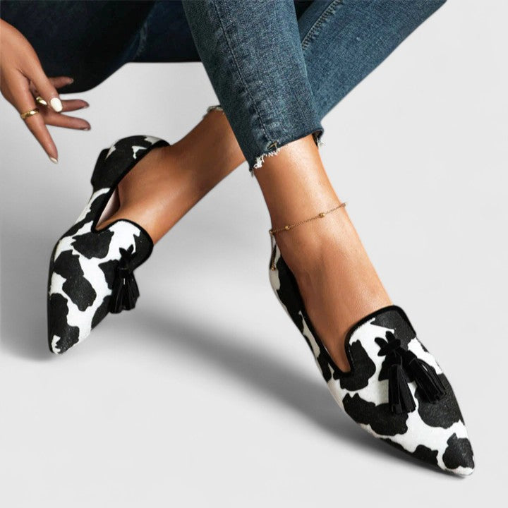 Tassel slip-on flats with black-and-white cow-print upper and black tassel detail
