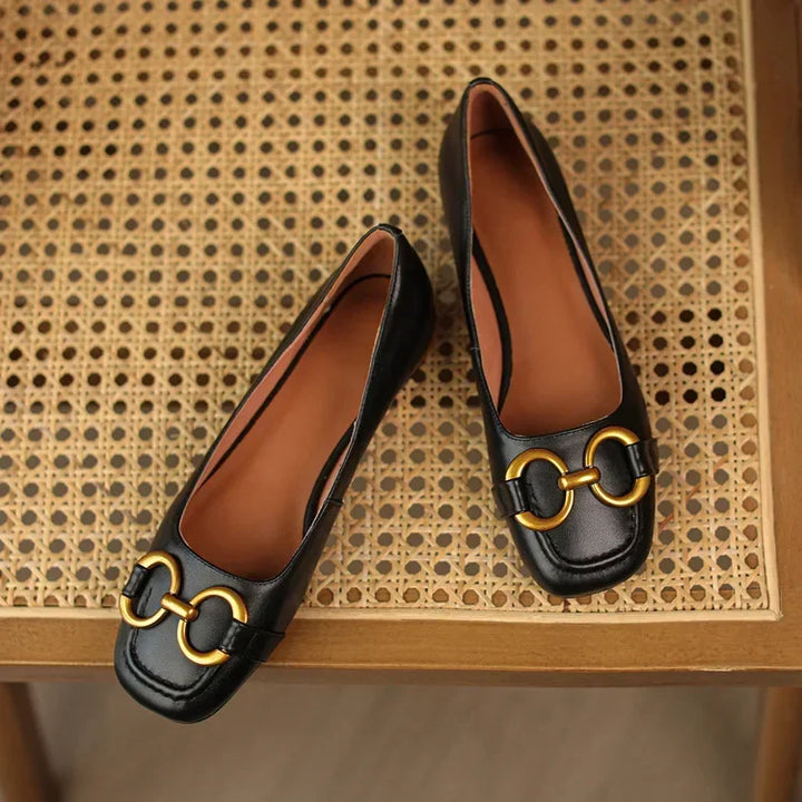Black ballet flats with gold chain-link buckle detail and tan lining
