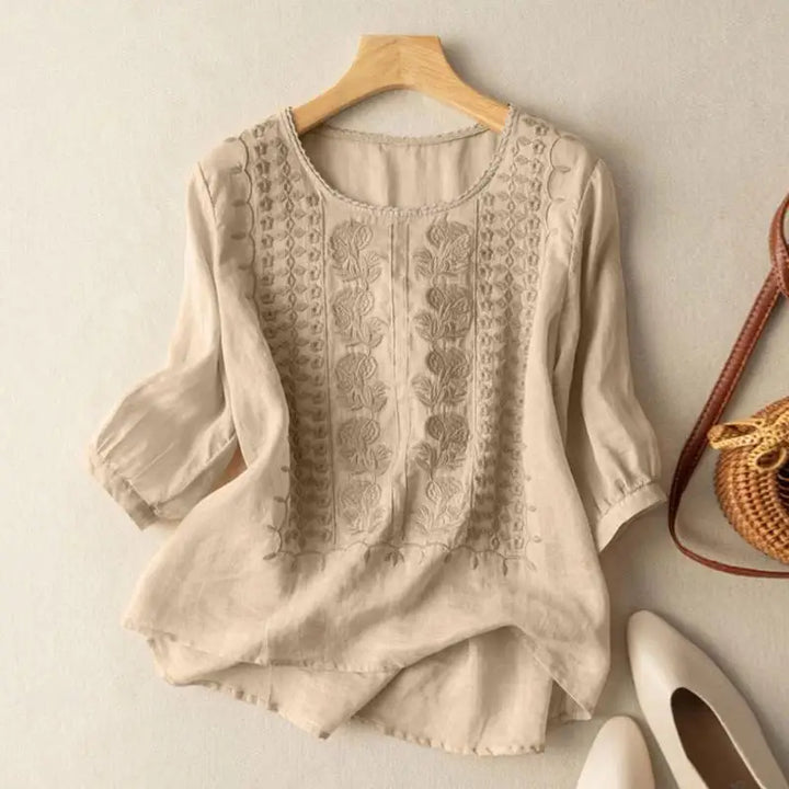 Beige embroidered blouse with vertical stitched panels and elbow-length puff sleeves
