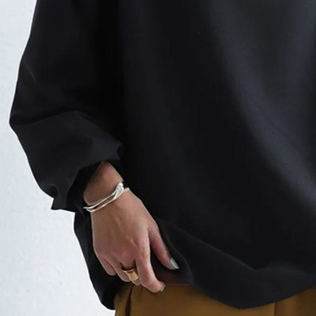 Black high-neck sweater sleeve close-up with cuff and draped fabric