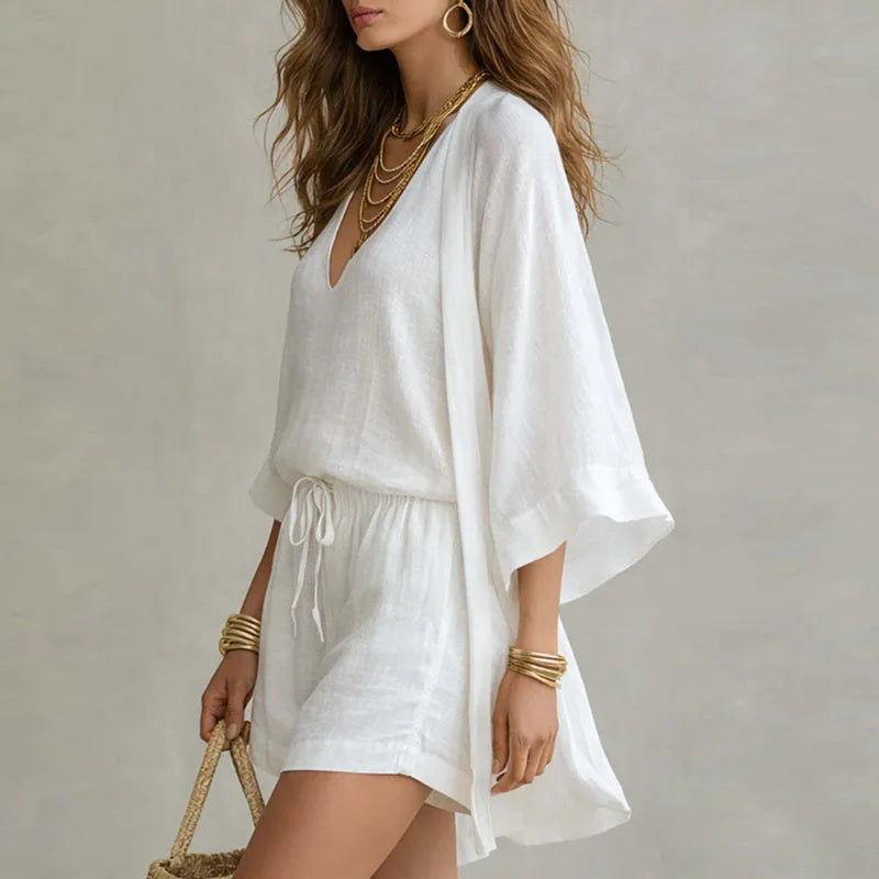 White linen V-neck top, drawstring waist shorts, and open kimono-style outer layer.
