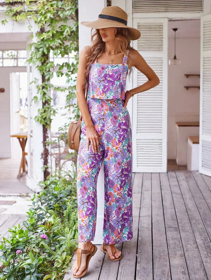 Purple floral wide-leg jumpsuit with smocked waist and wide, drapey legs.