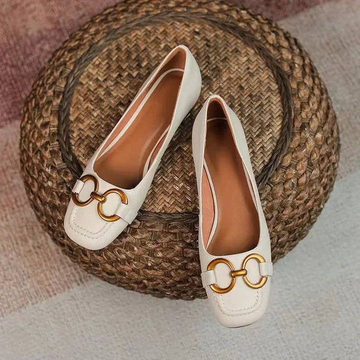 White ballet flats with gold chain-link ornament and curved moc-toe stitching
