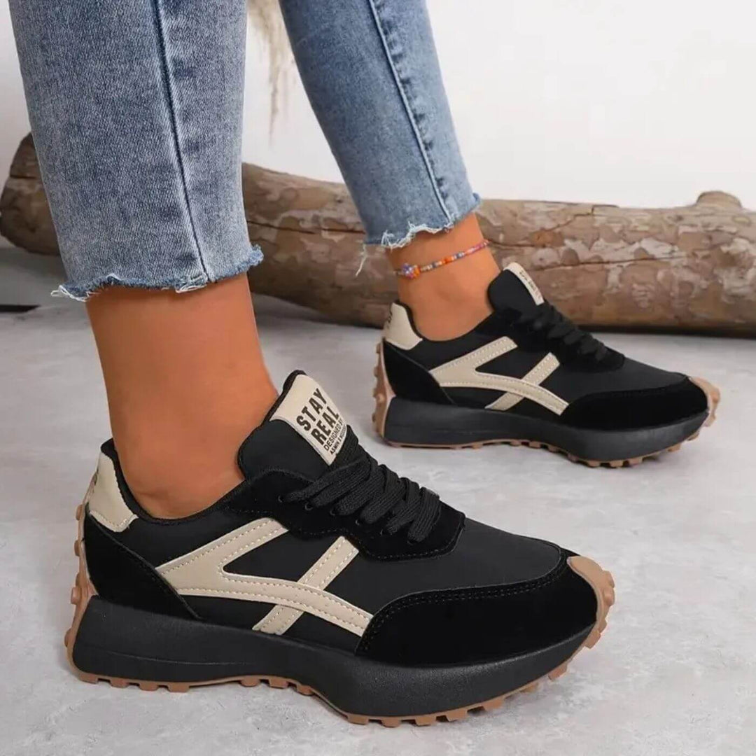 Black and beige lace-up trainers with chunky tread sole and 'STAY REAL' heel tab