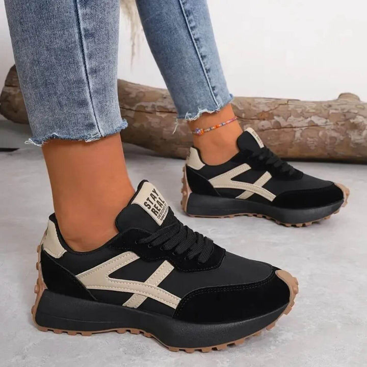 Black and beige lace-up trainers with chunky tread sole and 'STAY REAL' heel tab