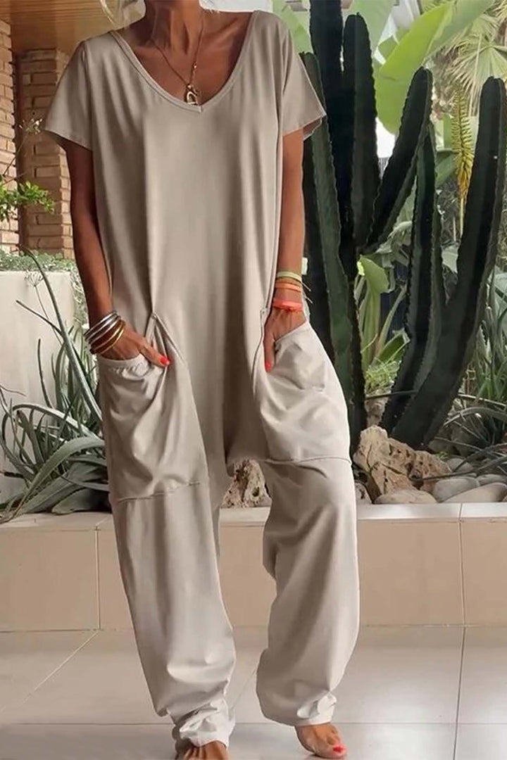 Stone beige relaxed pocket jumpsuit with V-neck, short sleeves, and roomy pant legs