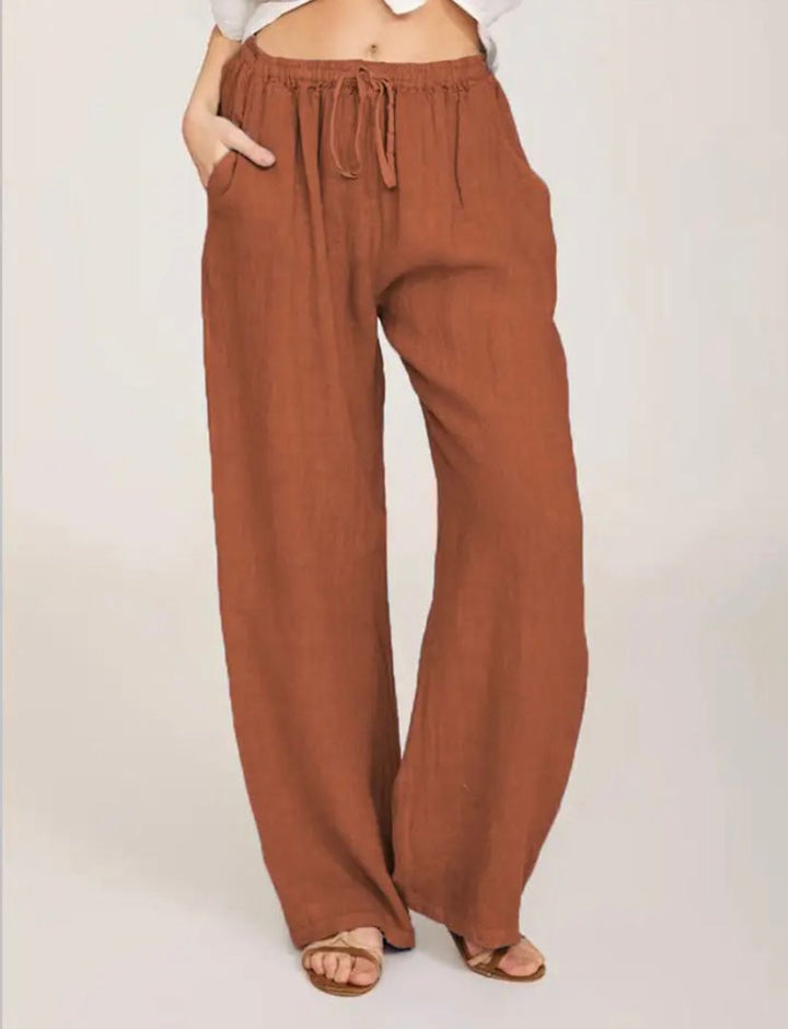 Rust brown drawstring pants with elastic waistband and relaxed wide-leg fit.