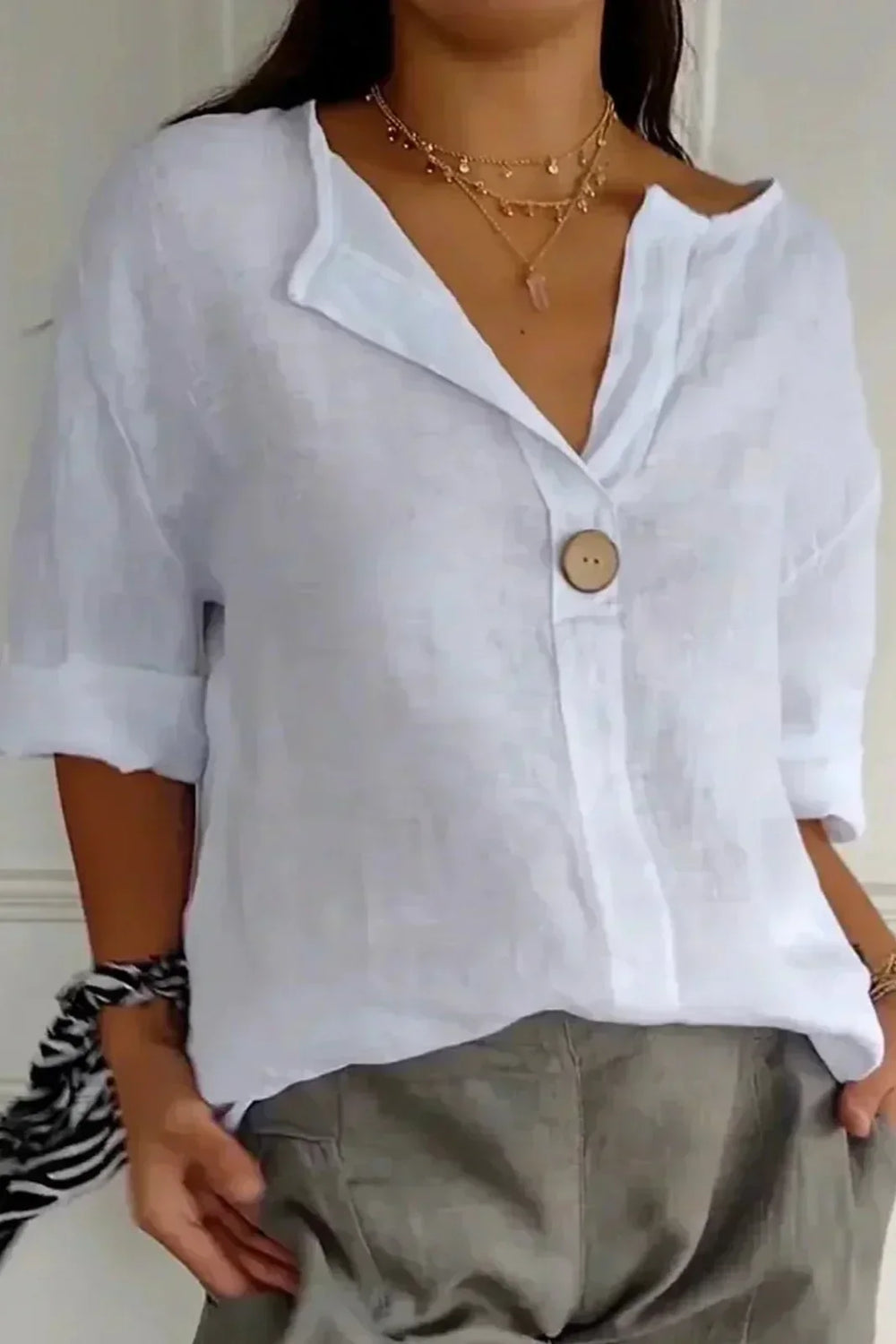 White minimal button blouse with V-neckline, half-length sleeves, and round front button