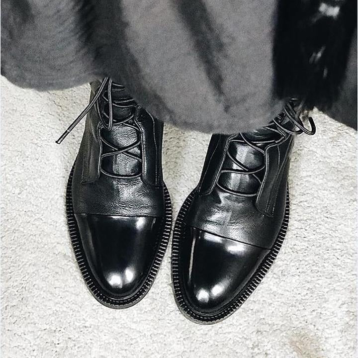 Black lace-up ankle boots with glossy finish, rounded toe, and thick ridged sole.