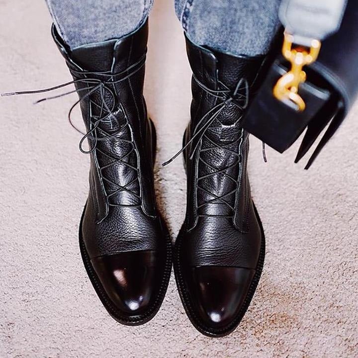 Black lace-up ankle boots with crisscross laces and pointed-sole profile on jeans.