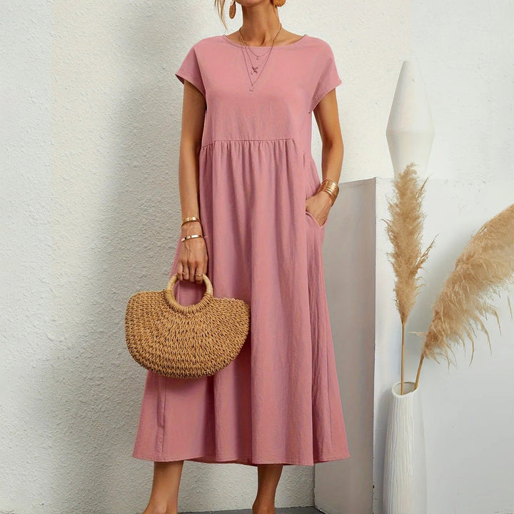 Pink midi dress with short sleeves, round neck, and gathered waist with a flowy skirt.