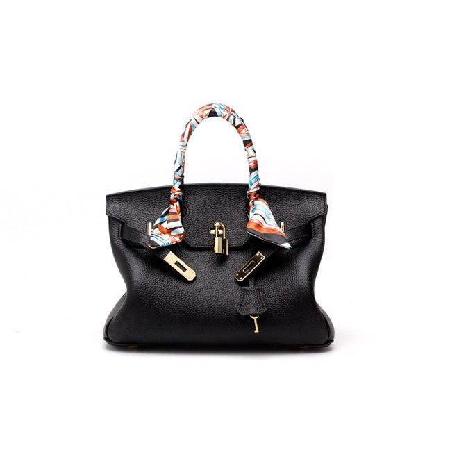 Black handbag with patterned scarf handles and front lock clasp; structured satchel shape