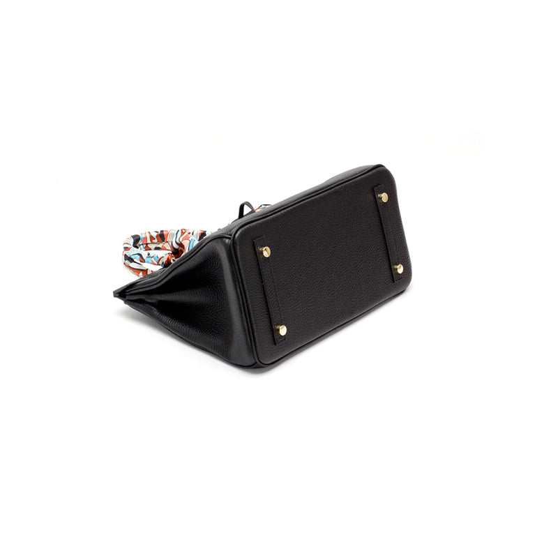 Black handbag with short handles, gold studs, and side panel detail; scarf at top