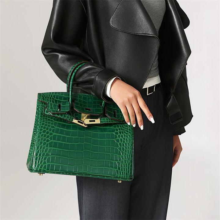 Green croc-embossed handbag with gold belt clasp and top handles.