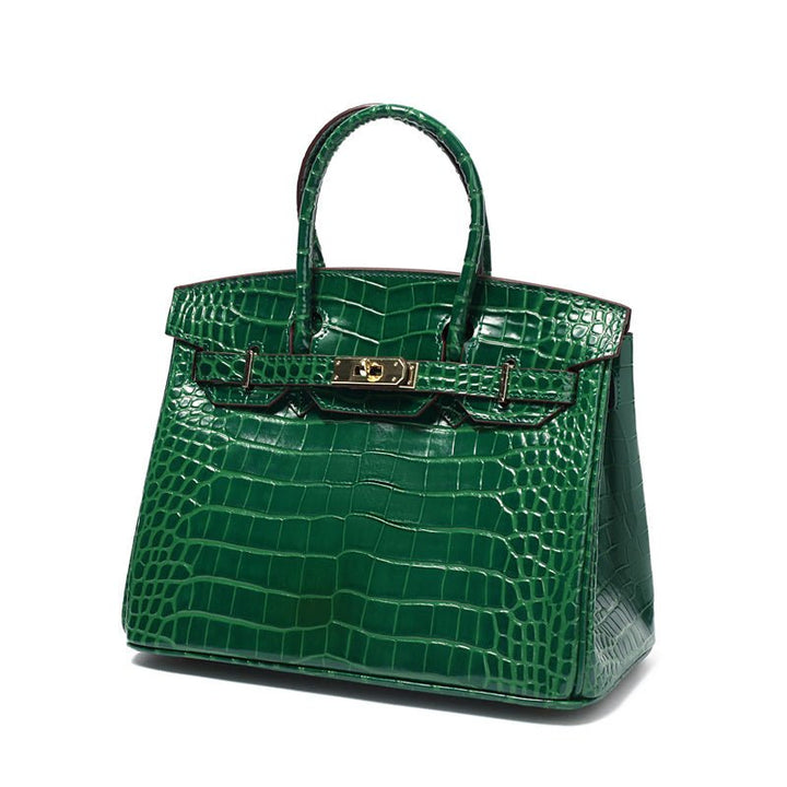 Green croc-embossed handbag with top handle, gold latch, and panel stitching.