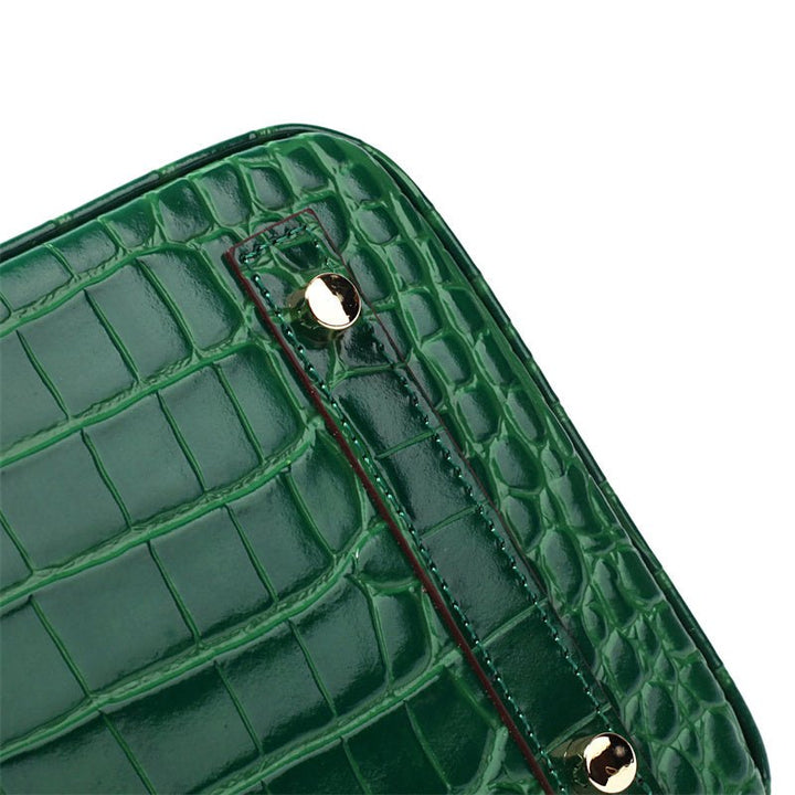 Green croc-embossed handbag side with snap rivets and gold hardware.