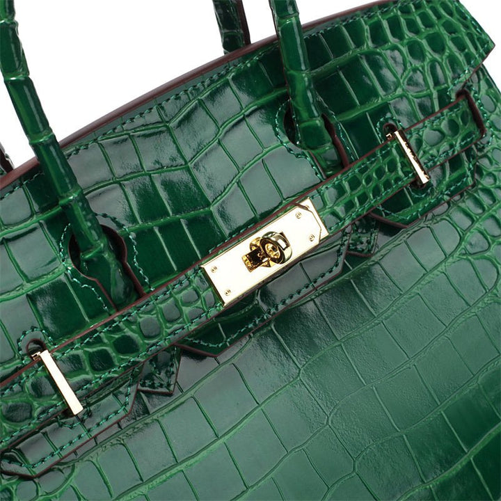 Green croc-embossed handbag detail with gold front clasp and stitched panels.