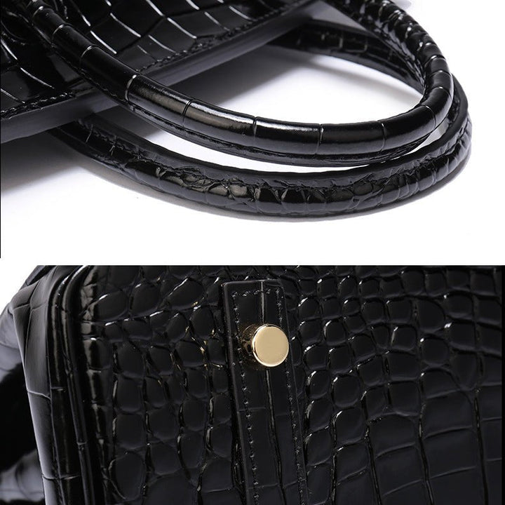 Black crocodile-textured handbag handle and front detail with gold-toned hardware