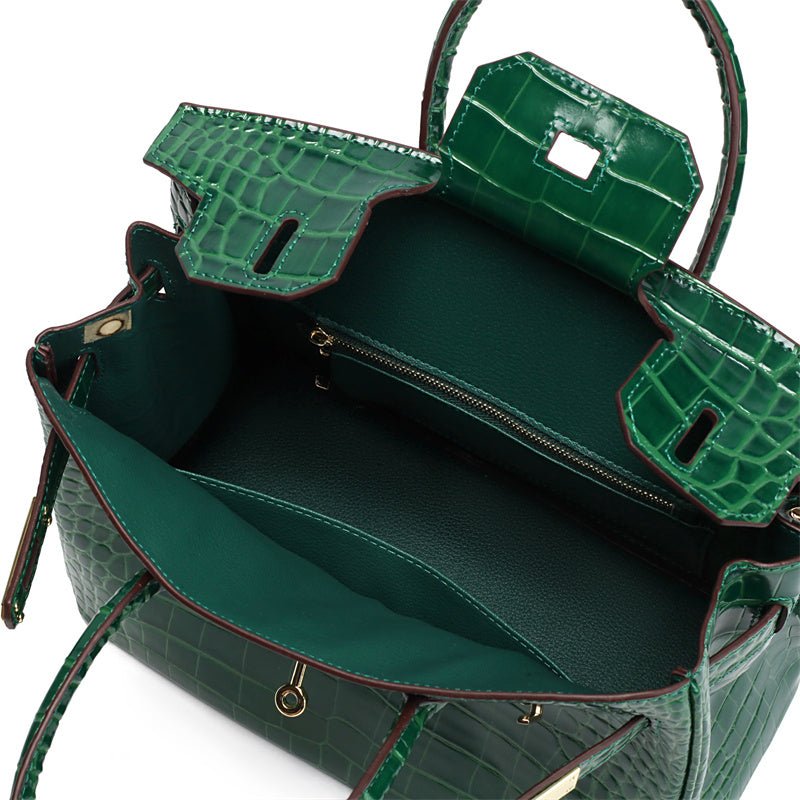 Green crocodile-textured handbag interior with top frame and front zip pocket