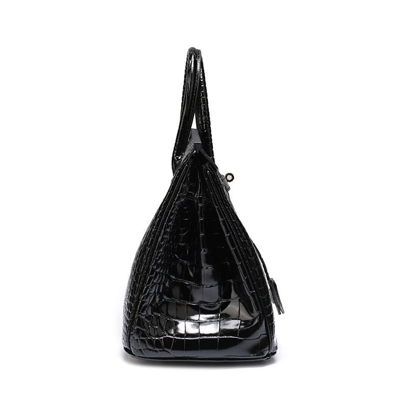 Black crocodile-textured handbag with curved top handle and small tassel zipper pull