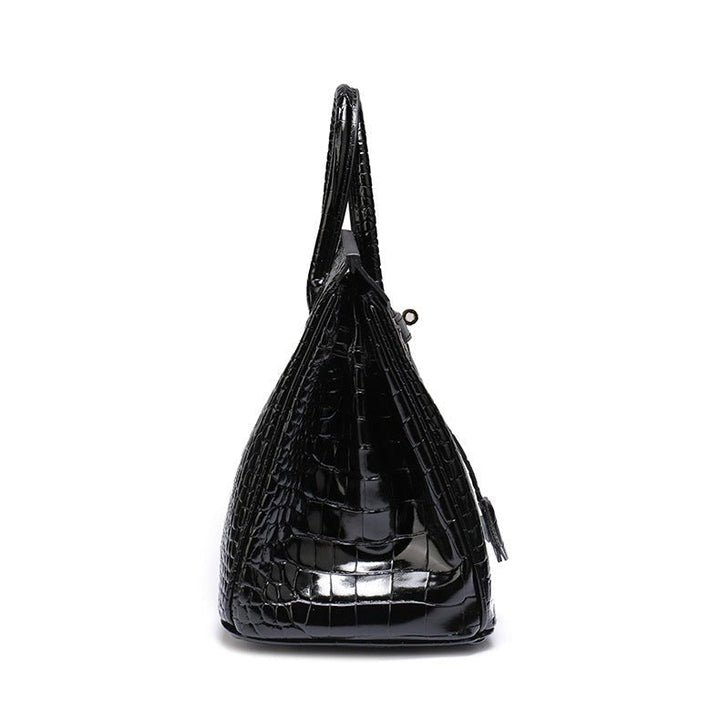 Black crocodile-textured handbag with curved top handle and small tassel zipper pull