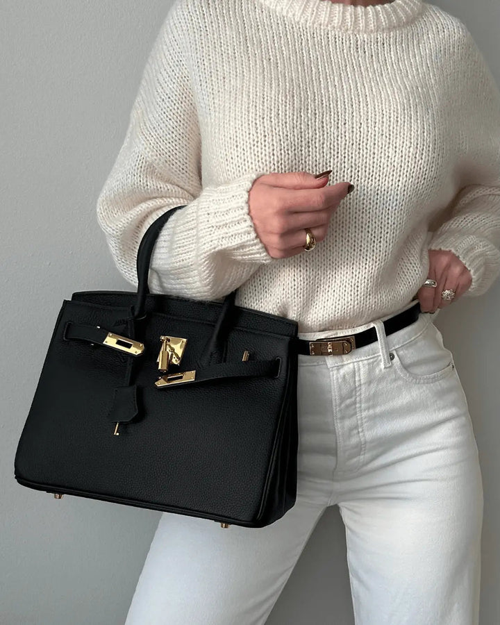 Black structured handbag with top handle, gold-tone lock detail, and front flap