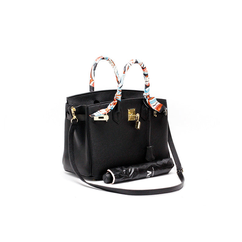 Black leather handbag with top handles and colorful scarf ties, gold-tone hardware.
