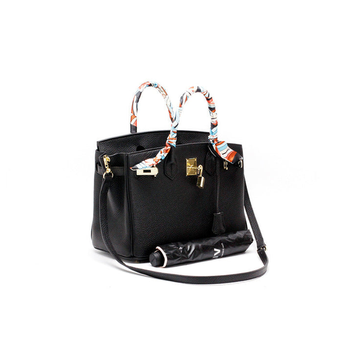 Black leather handbag with top handles and colorful scarf ties, gold-tone hardware.