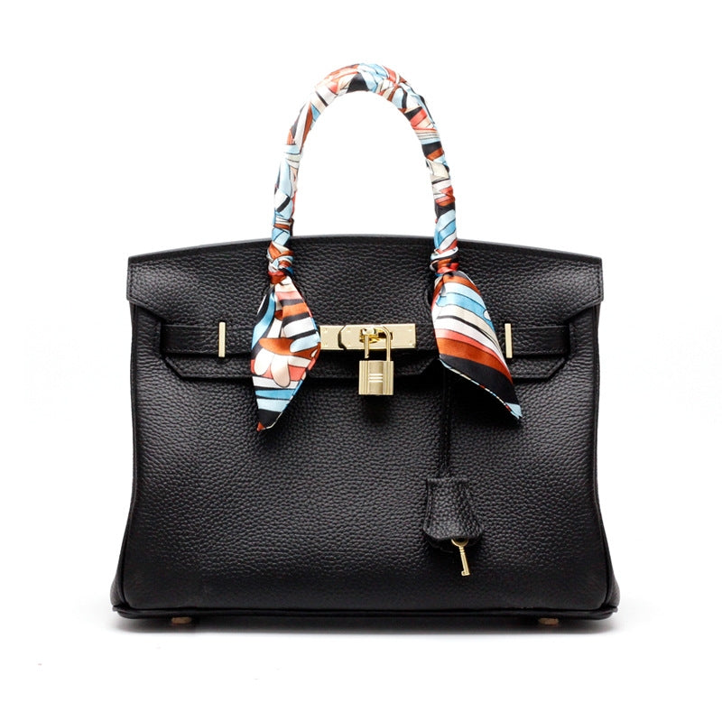 Black structured handbag with scarf-tie handles and gold lock clasp