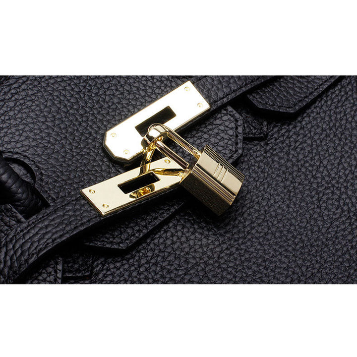 Black textured leather handbag clasp with gold hardware.
