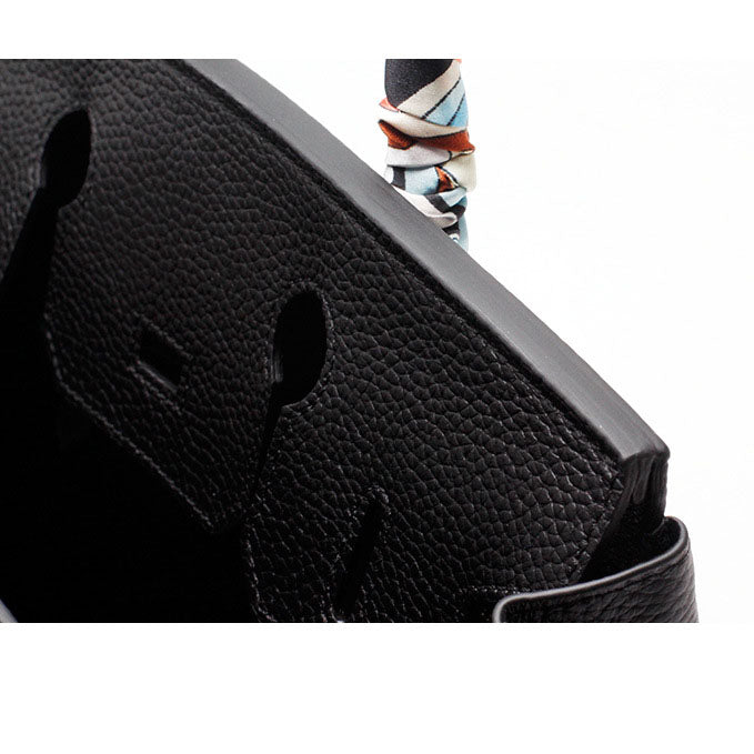 Black pebbled leather handbag corner with cutout detail and rounded edge stitching.
