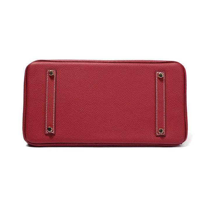 Wine red leather handbag front with rectangular hardware accents and clean flat base.