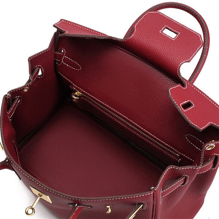 Wine red leather handbag open interior view with zipper track and gold-tone hardware.