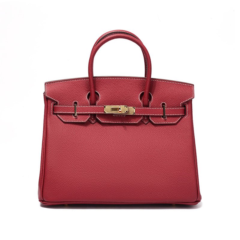 Structured leather handbag with top handles, front clasp bar, and gold hardware in wine red.
