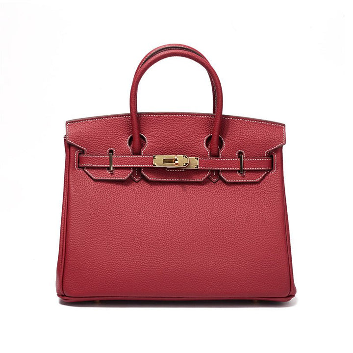 Structured leather handbag with top handles, front clasp bar, and gold hardware in wine red.